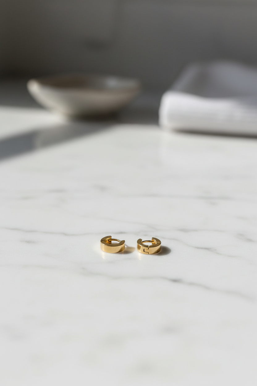 Gold huggie hoop earrings on cream satin fabric