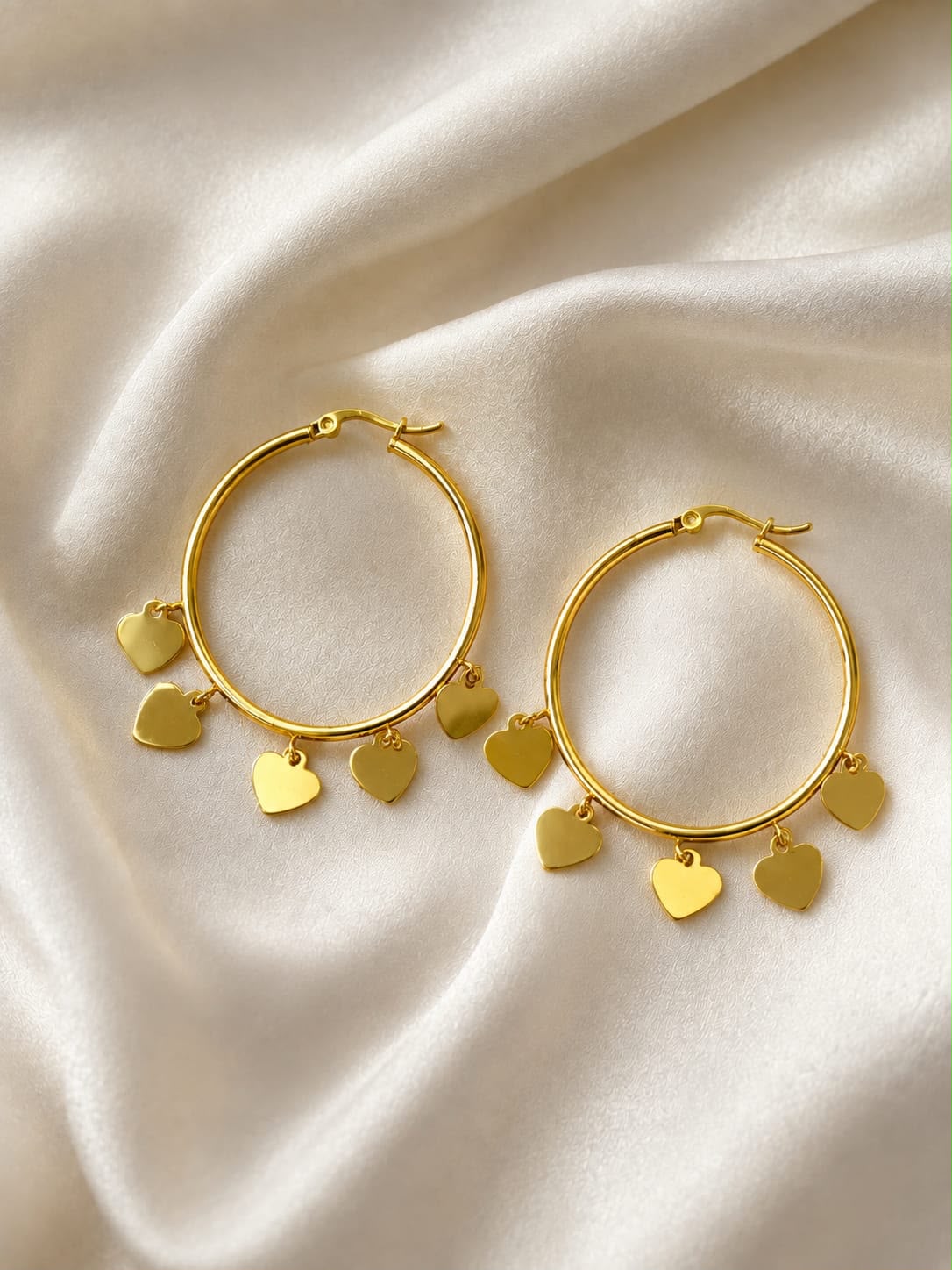 Gold Heart Charm Hoop Earrings on cream satin fabric