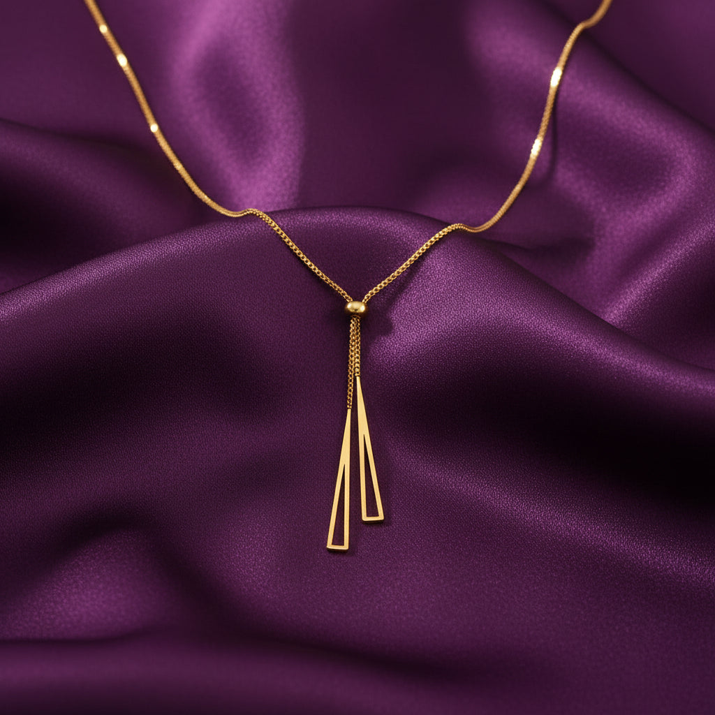 Gold geometric triple-bar tassel lariat necklace worn on model with cream satin backdrop