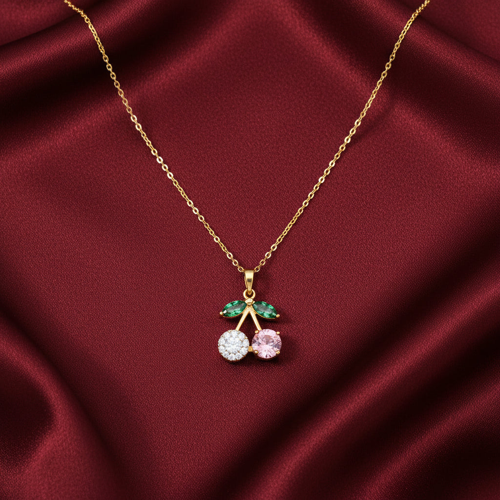Crystal cherry pendant necklace with pavé and pink stone cherries worn on model with cream satin backdrop